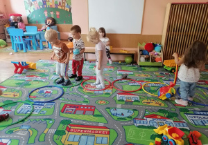 Przedszkolaki z grupy I skaczą na dywanie do obręczy.