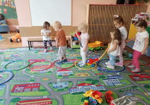 Przedszkolaki skaczą na dywanie do obręczy.