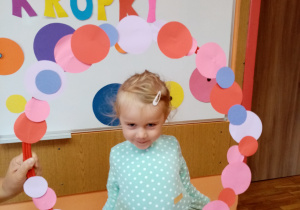 Dziewczynka pozuje do zdjęcia w ramce z kropkami.