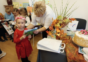 Lila odbierająca tomik wierszy od pań organizatorek konkursu