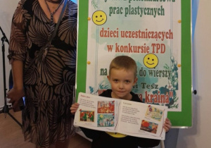 Marcel z nauczycielką na tle plakatu - Wystawa pokonkursowa