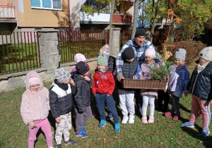 Dzieci z panem Rafałem trzymają skrzynkę z sadzonkami