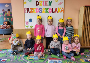 Chłopcy z grupy najmłodszej stoją na tle tablicy Dzień Przedszkolaka.