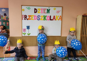 Chłopcy z grupy najmłodszej stoją na tle tablicy Dzień Przedszkolaka.