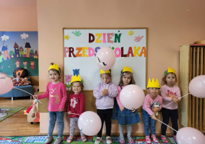 Dziewczynki z grupy najmłodszej stoją na tle tablicy Dzień Przedszkolaka.