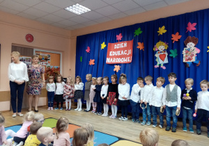 Grupa „Słoneczka” wraz z nauczycielkami na tle dekoracji Dzień Edukacji Narodowej.