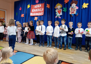 Dziewczynka dyryguje, a dzieci grają na instrumentach.