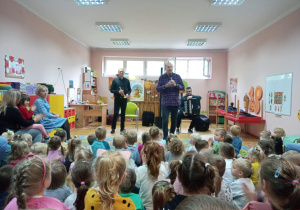 Przedszkolaki słuchają muzyków.
