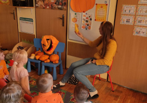 Nauczycielka przed tablicą opowiada ciekawostki o dyni.