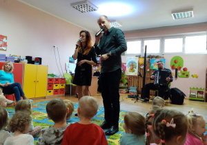 Prowadzący wraz z wokalistką śpiewają piosenkę.
