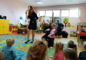 Dziewczynka wraz z wokalistką śpiewa piosenkę.
