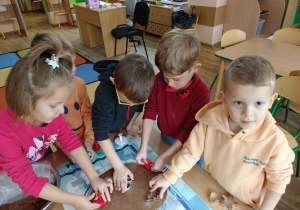 Dzieci foremkami wykrawają w cieście pierniki