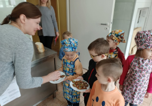 Dzieci częstują piernikami panie w kuchni
