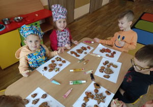 Dzieci ozdabiają cukierniczymi pisakami pierniki