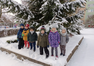Dzieci stoją na tle ośnieżonego drzewa