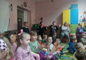 Dzieci oraz nauczycielki machają rękoma w rytm muzyki.