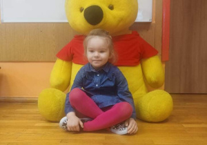 Dziewczynka pozuje do zdjęcia z pluszowym Kubusiem Puchatkiem.