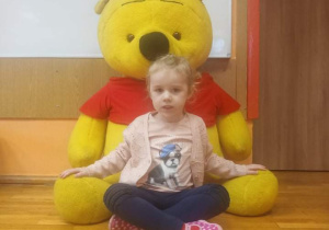 Dziewczynka pozuje do zdjęcia z pluszowym Kubusiem Puchatkiem.