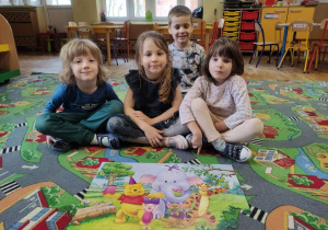 3Dzieci prezentują ułożone puzzle z serii „Kubuś Puchatek i przyjaciele”.