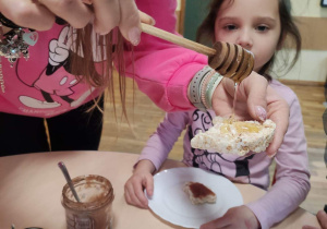 Nauczycielka polewa wafelek miodem.