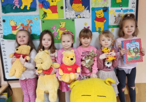 Zdjęcie dzieci z przytulankami i na tle prac plastycznych z Kubusiem Puchatkiem