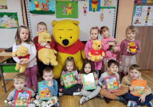 Pamiątkowe zdjęcie dzieci z maskotkami i książkami.