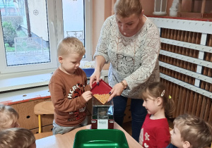 Pani z dziećmi napełnia maszyne do popcornu ziarenkami kukurydzy