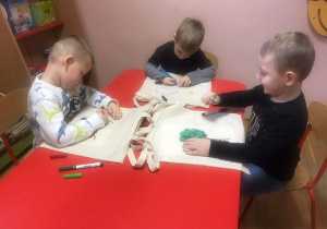 Chłopcy ozdabiają markerami płócienne torby.