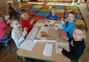 Dzieci jedzą pizzę