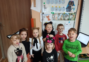 Dzieci w przebraniach kotków na tle tablicy z kotami