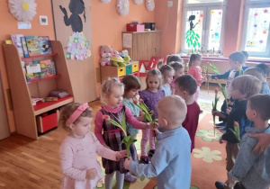 Każdy chłopiec wręcza kwiatka swojej koleżance.