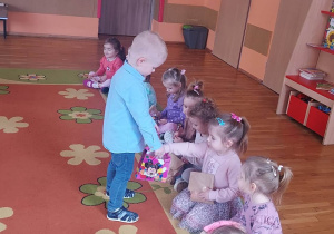 Chłopiec częstuje dziewczynki słodkościami.