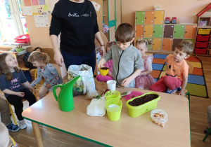 Chłopiec wsypuje ziemię do doniczki