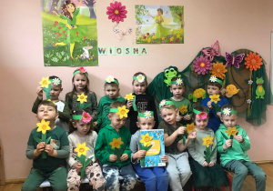 Przedszkolaki z grupy III w wiosennej scenerii z wykonanymi przez siebie żonkilami.