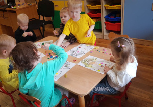 Przedszkolaki z grupy I ozdabiają naklejkami suknię Pani Wiosny.