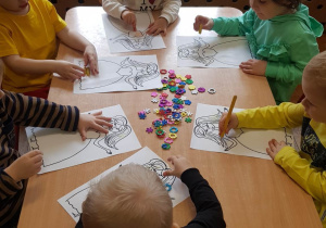 Przedszkolaki z grupy I ozdabiają naklejkami suknię Pani Wiosny.