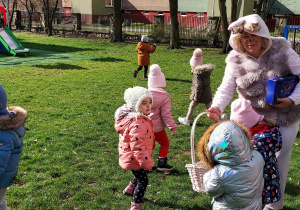 Zajączek częstuje dzieci cukierkami.