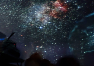 Dzieci obserwują gwieździste niebo w mobilnym planetarium.