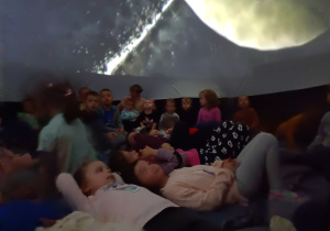 Dzieci w mobilnym planetarium obserwują inne planety