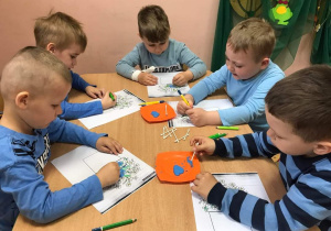 Dzieci robią pracę plastyczną "Niezapominajki"