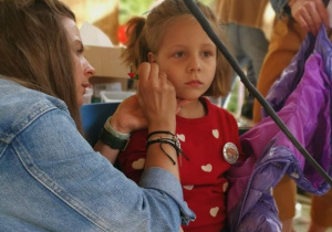 Pani maluje policzek dziewczynki
