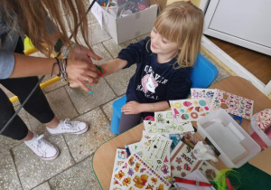 Pani wykonuje samoprzylepny tatuaż na ręce dziewczynki