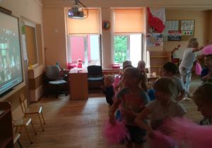 Dzieci z pomponami tańczą.