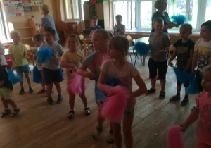 Dzieci z pomponami tańczą.