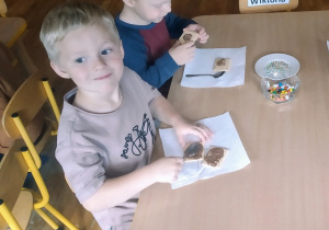 Dwóch chłopców smaruje herbatniki płynną czekoladą.
