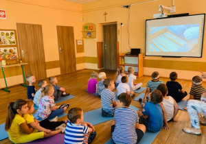 Dzieci oglądają prezentacje na temat procesu powstawania miodu
