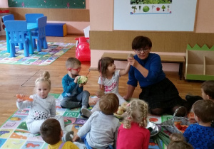 Nauczycielka pokazuje dzieciom warzywa, dzieci trzymają naturalne okazy warzyw.