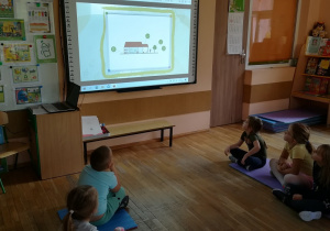 Dzieci patrzą na tablicę multimedialną