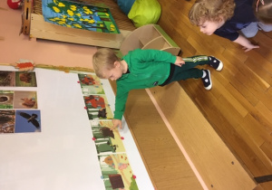 chłopiec pokazuje na obrazku domek świnki z drewna