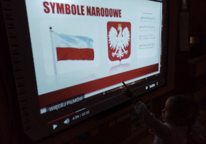 Dziewczynka pokazuje na slajdzie symbole narodowe.